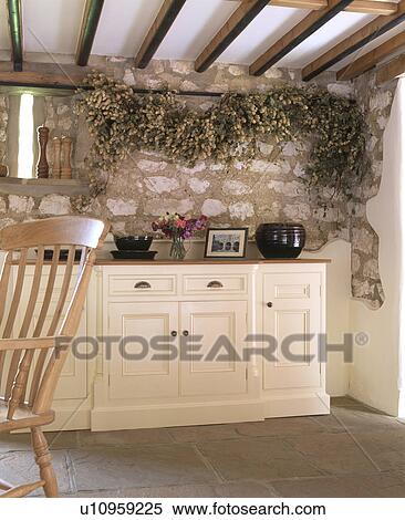 Stock Photography - Hope garland on exposed stone wall above cream fitted unitin traditional country kitchen. Fotosearch