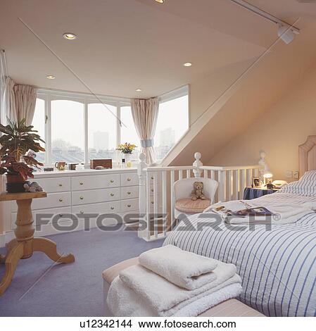 Houseplant on wooden stand in converted attic bedroom with striped duvet and mauve carpet View Large Photo Image Picture - Houseplant on wooden stand in converted attic bedroom with striped duvet and mauve carpet. Fotosearch