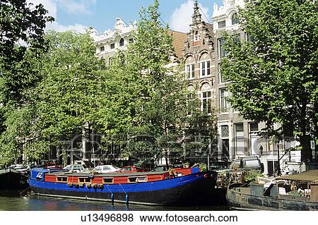 Stock Photo - Houses overlooking canal and houseboat, Amsterdam, Holland. Fotosearch