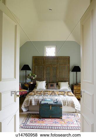 Indian Trellis Screen Above Bed In Grey And Cream Bedroom With Blue Painted Chest At The End Of The Bed Stock Photo