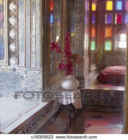 Stock Image - Intricately patterned blue+white mosaic walls and brightly coloured stained glass windows in Rajastani bedroom. Fotosearch