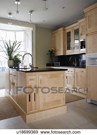 Stock Photo - Island unit in modern townhouse kitchen with pale wood units. Fotosearch