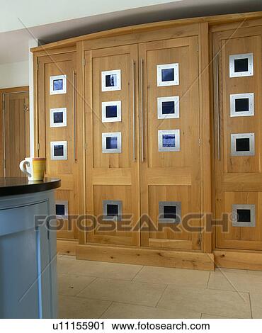 Stock Image - Large fitted oak cupboard concealing fridge-freezer in modern kitchen. Fotosearch