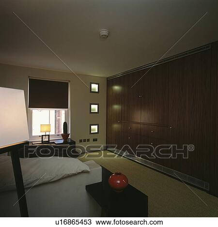 Stock Image - Large fitted wardrobe in modern townhouse bedroom. Fotosearch