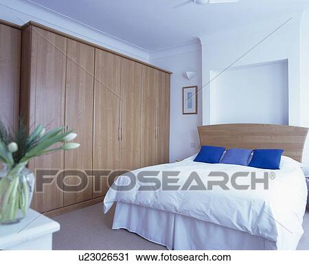Stock Image - Large fitted wardrobe in modern white bedroom. Fotosearch