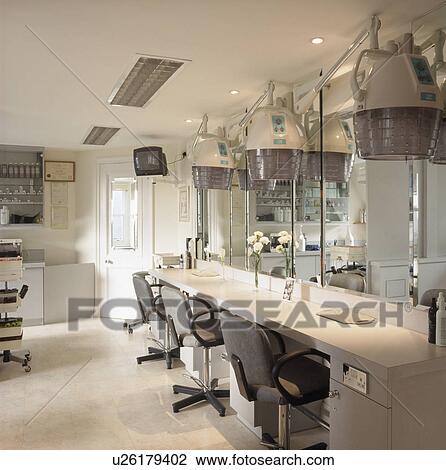 Stock Image - Large hair-dryers above counter in hair-dressing salon. Fotosearch
