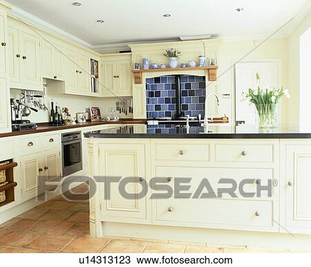 Stock Image - Large island unit in traditional cream country kitchen. Fotosearch