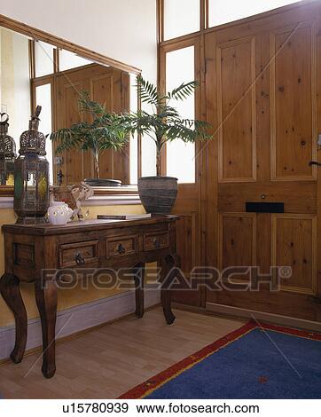 Stock Photo - Large mirror above console table with potted palm in townhouse hall. Fotosearch