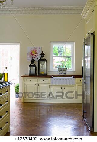 Stock Image - Large Moroccan lanterns on worktop in cream country kitchen with parquet floor. Fotosearch