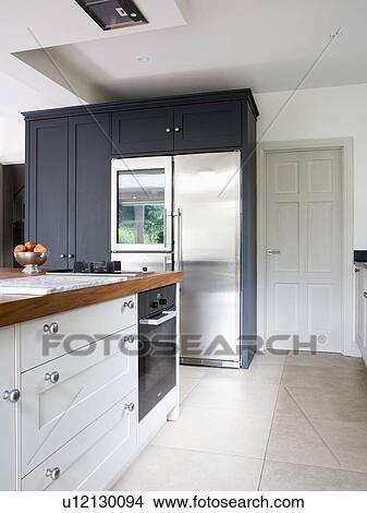 Picture - Large stainless steel American-style fridge freezer in modern white kitchen. Fotosearch