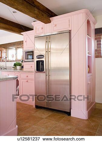 Stock Photo - Large stainless steel American-style fridge-freezer in pastel pink fitted unit in country kitchen . Fotosearch