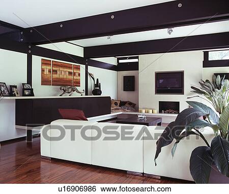 Large White Sofa In Modern White Living Room With Black Ceiling Beams Stock Photograph