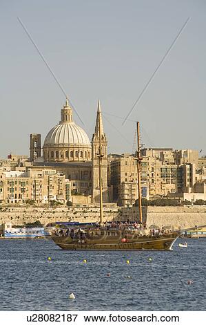 Stock Photo - Large yacht cruising in front of old builings in Sliema harbour in Valletta on the island of Malta. Fotosearch