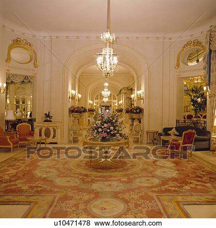 Stock Photo - Lighted chandelier above circular table in hotel foyer. Fotosearch