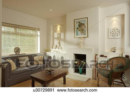 Lighted cream alcoves on either side of fireplace in cream living room with wicker armchair View Large Photo Image Stock Image - Lighted cream alcoves on either side of fireplace in cream living room with wicker armchair. Fotosearch
