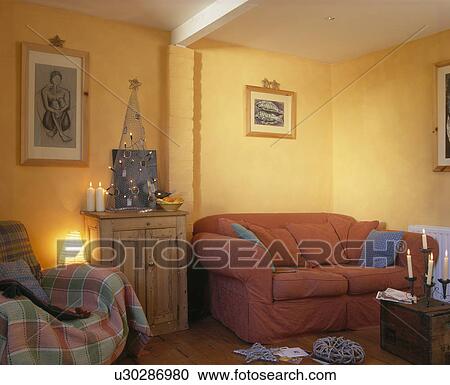 Stock Image - Lighted lamp and red sofa in yellow economy-style living room with metal Christmas tree. Fotosearch