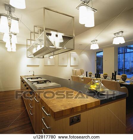 Stock Image - Lighting above island unit in large modern kitchen dining room. Fotosearch