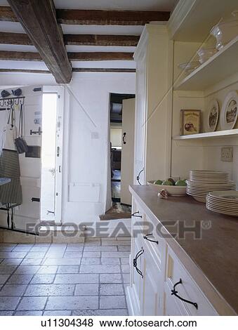 Stock Photo - Limestone floor tiles in white cottage kitchen. Fotosearch
