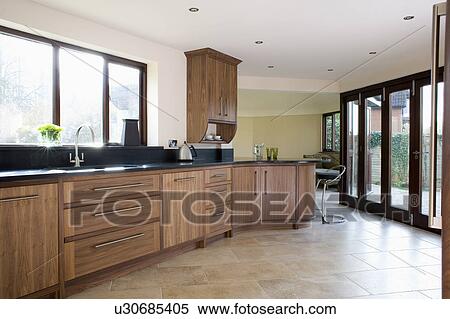 Limestone flooring and glass patio doors in modern kitchen with fitted walnut units View Large Photo Image Stock Photography - Limestone flooring and glass patio doors in modern kitchen with fitted walnut units. Fotosearch