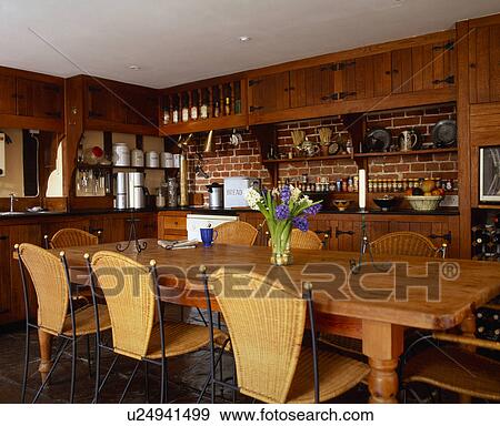 Stock Photo - Long pine table and modern wicker chairs in country kitchen. Fotosearch