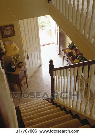 Stock Photograph - Looking down staircase into traditional cream country hall. Fotosearch