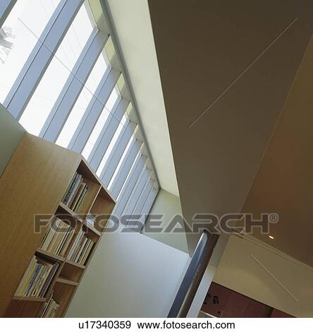 Looking up at bookcase and large windows in modern living room View Large Photo Image Stock Photo - Looking up at bookcase and large windows in modern living room. Fotosearch