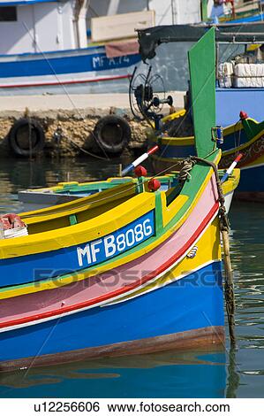 Stock Photograph - Luzzu fishing boat moored in Marsaxlokk Harbour, Marsaxlokk, Malta. Fotosearch