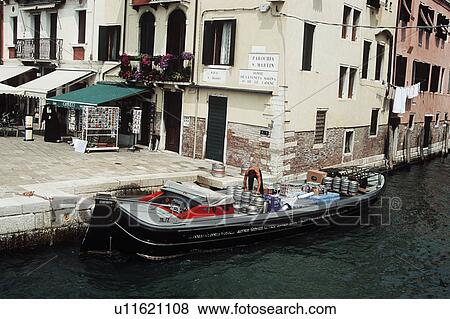 Stock Photo - Man and beer crates on transport boat on Venetian canal&#10;. Fotosearch