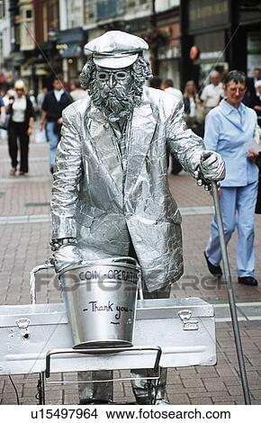Picture - Man dressed in silver clothing and coated in silver paint, pushing trolley, Dublin, Southern Ireland. Fotosearch