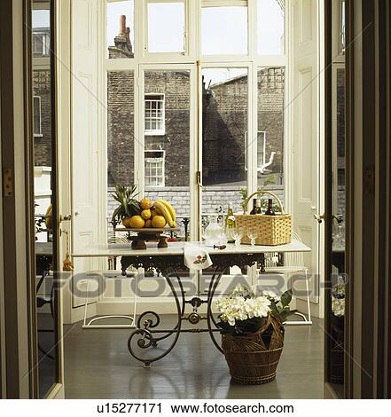 Marble-topped metal table in front of French windows in townhouse dining room View Large Photo Image Stock Image - Marble-topped metal table in front of French windows in townhouse dining room. Fotosearch