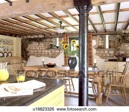 Stock Photograph - Metal pillar roof support in country kitchen dining room with beamed ceiling. Fotosearch