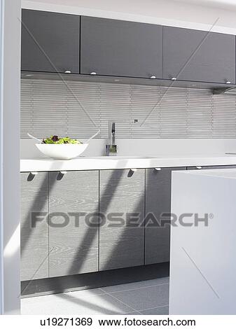 Metal splashback above fitted units in modern black and white kitchen View Large Photo Image Stock Photo - Metal splashback above fitted units in modern black and white kitchen. Fotosearch