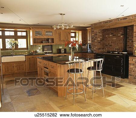 Metal stools at breakfast bar on island unit in country kitchen with limestone flooring View Large Photo Image Stock Image - Metal stools at breakfast bar on island unit in country kitchen with limestone flooring. Fotosearch