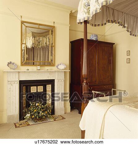 Stock Image - Mirror above marble fireplace in tradtional bedroom. Fotosearch