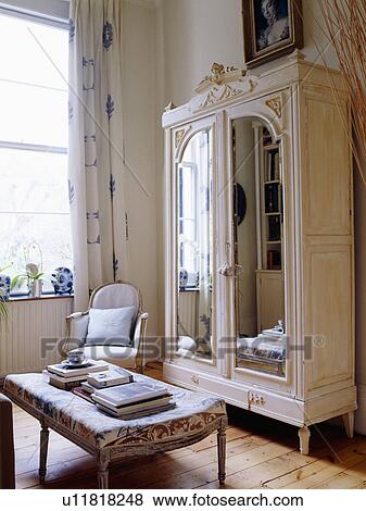 Stock Photo - Mirror-fronted painted white cupboard in white living room. Fotosearch