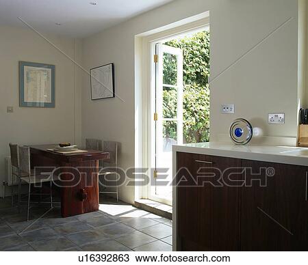 Modern kitchen dining room with table and chairs in corner beside open French windows View Large Photo Image Stock Image - Modern kitchen dining room with table and chairs in corner beside open French windows. Fotosearch