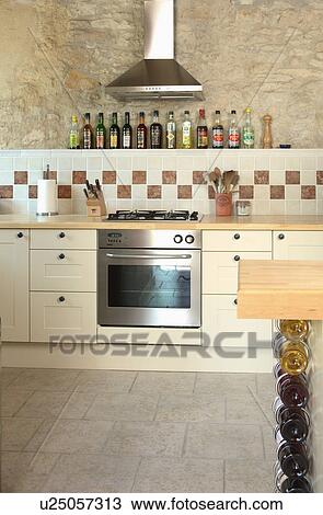 Stock Image - Modern kitchen in stone building with neutral coloured materials and beamed ceiling.. Fotosearch