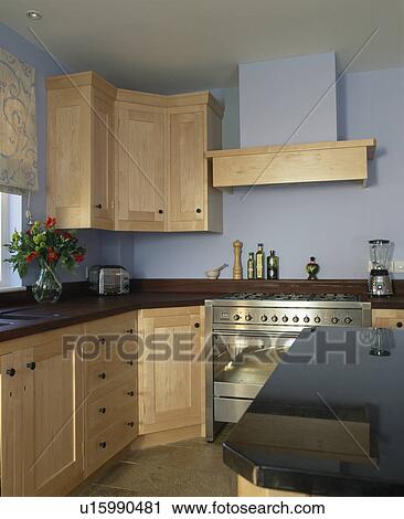 Stock Image - Modern pastel blue kitchen with pale wood fitted units. Fotosearch