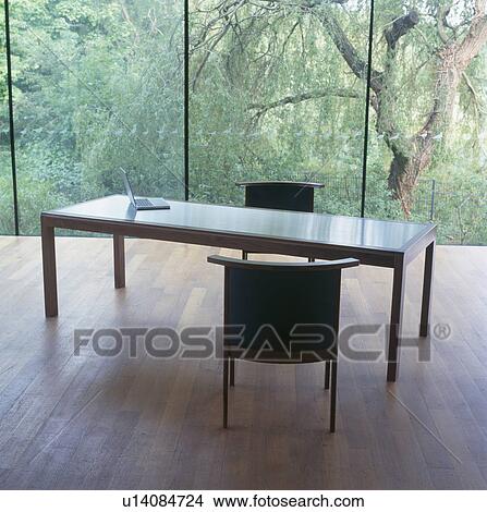 Modern rectangular table and black chairs in minimalist home office with plate glass windows View Large Photo Image Picture - Modern rectangular table and black chairs in minimalist home office with plate glass windows. Fotosearch