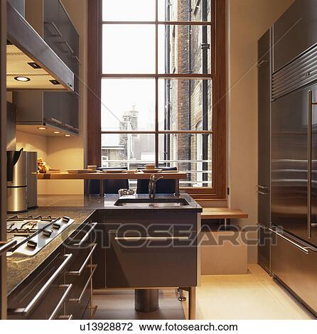 Stock Image - Modern townhouse kitchen with steel handles on granite-topped units. Fotosearch