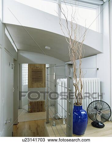Stock Image - Modern white architectural landing with willow branches in blue vase. Fotosearch