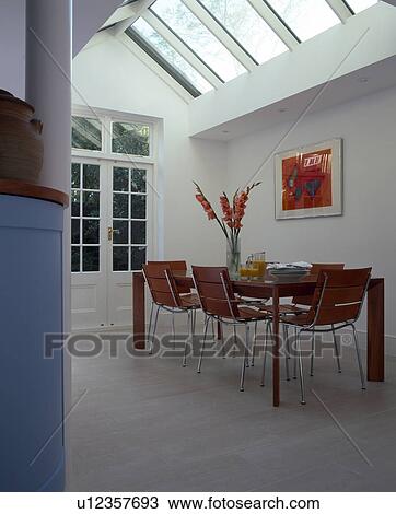 Stock Image - Modern white conservatory dining room with glass apex ceiling. Fotosearch