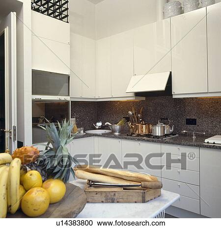 Stock Image - Modern white kichen with lacquered white cupboards and black granite splashback and worktops. Fotosearch