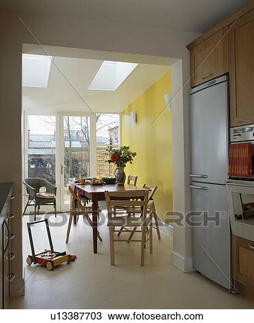 Modern yellow dining room extension with cream flooring and wooden table and chairs View Large Photo Image Stock Image - Modern yellow dining room extension with cream flooring and wooden table and chairs. Fotosearch
