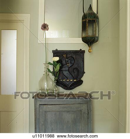 Stock Photo - Moroccan lantern above grey painted cupboard with tall glass vase in small cream hall. Fotosearch
