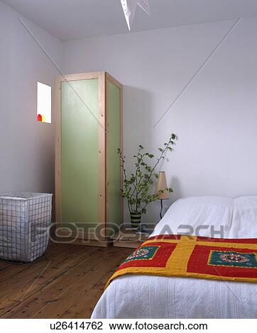 Narrow green wardrobe in modern white bedroom with colourful throw on bed View Large Photo Image Stock Image - Narrow green wardrobe in modern white bedroom with colourful throw on bed. Fotosearch