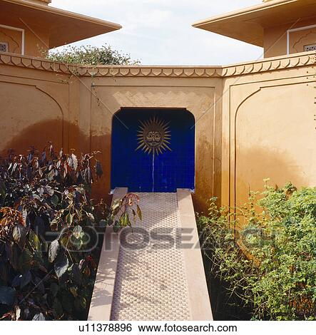 Stock Photograph - Narrow marble bridge to Indian sculpture in blue tiled alcove in sandstone courtyard in Rajastan. Fotosearch