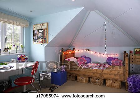Picture - Novelty fairy lights above wooden bed in teenager's attic bedroom. Fotosearch