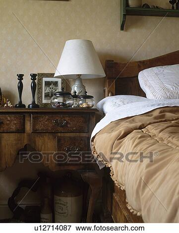 Stock Photo - Old-fashioned beige eiderdown on bed with white bedlinen in country bedroom. Fotosearch