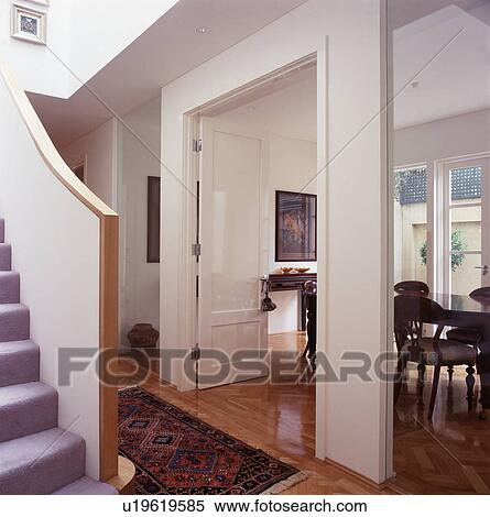 Stock Photography - Open double doors to dining room in openplan modern white hall. Fotosearch